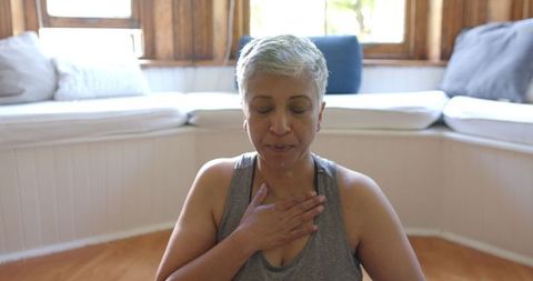 Calm senior woman practicing meditation at home