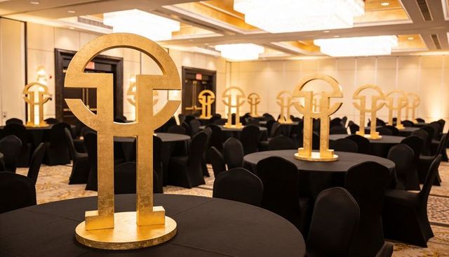 Gold circular centerpieces elevating black banquet tables in luxury ballroom