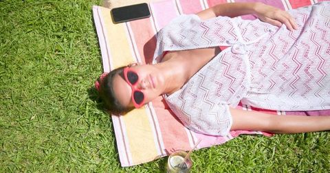 Woman Sunbathing Outdoors on Colorful Towel Wearing Red Sunglasses