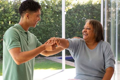 Grandson Helping Grandmother Stretch on Sunny Patio