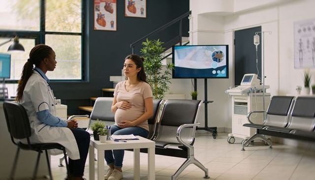 Pregnant woman consulting doctor in clinic during prenatal appointment, ultrasound visible