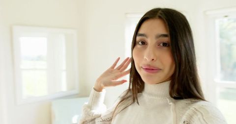 Elegant Woman in Cozy Sweater Enjoys Natural Light At Home