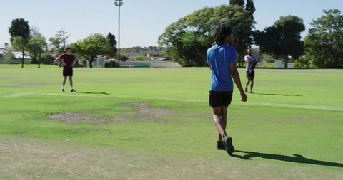 African american athlete pausing before bowling on cricket field during training