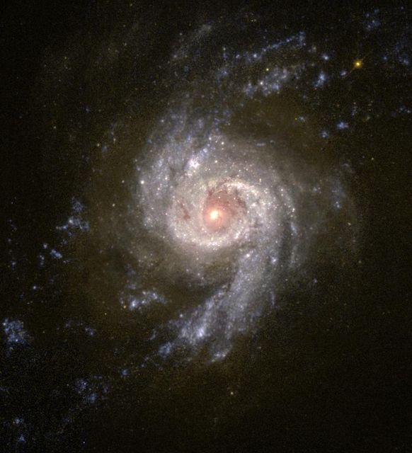 Detailed view of a star cluster in a spiral galaxy captured by NASA's Hubble Space Telescope. The image reveals the galaxy's bright core and spiral arms, useful for illustrating concepts in astronomy, space exploration, and scientific research. Ideal for educational materials, science presentations, and articles discussing the age and history of starburst galaxies.