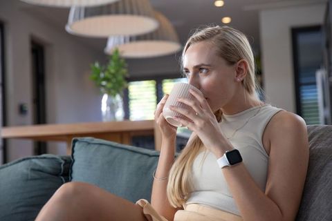 Young Woman Relaxed on Sofa Holding Ceramic Mug in Modern Living Room