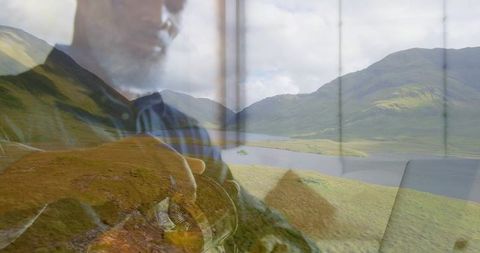 Double exposure man holding round object gazing through window at lake valley reflection