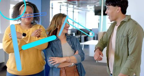 Young professionals chatting and laughing in modern open office during casual team huddle