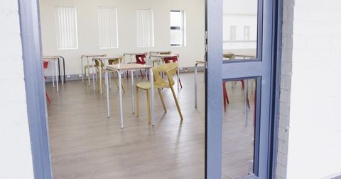 Empty classroom interior with open blue-framed door and modern design