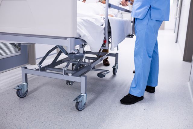 Low-section of a doctor taking patient to operation theatre on a stretcher