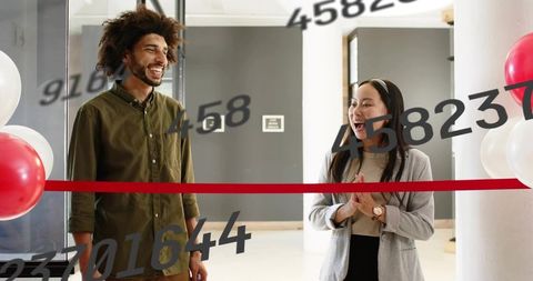 Colleagues celebrating ribbon-cutting, laughing with red balloons in office lobby