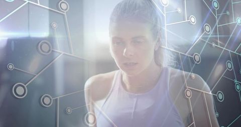 Focused female athlete breathing and training in backlit gym with digital network overlay