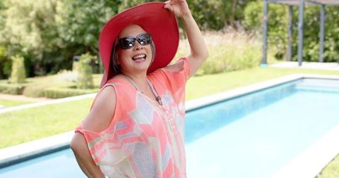 Senior Woman in Sunhat and Sunglasses Enjoying Poolside