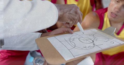 Sports coach explaining strategy with clipboard to team