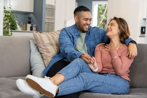 Laughing couple relaxing on sofa in modern open-plan living room