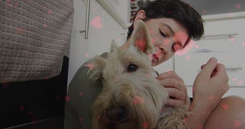 Woman embracing terrier dog with heart overlay in home kitchen