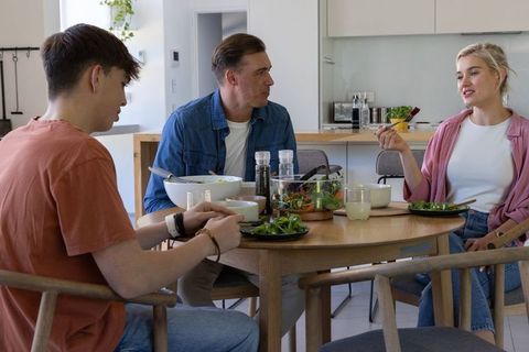Family sharing healthy dinner around wooden table in bright modern kitchen