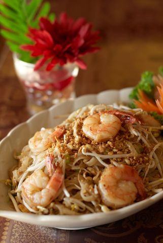 Serving shrimp pad thai with crushed peanuts, bean sprouts and garnish
