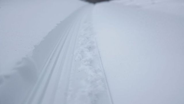 Single snow track cutting through powder snow, minimal winter texture and soft groove