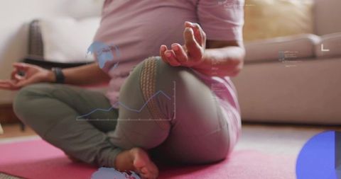 Senior woman meditating on pink yoga mat at home wearing smartwatch with data overlays