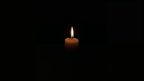 Solitary Candle Illuminating Dark Room with Warm Glow