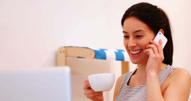 Smiling Woman Drinking Coffee and Talking on Phone at Home Office - Download Free Stock Images Pikwizard.com