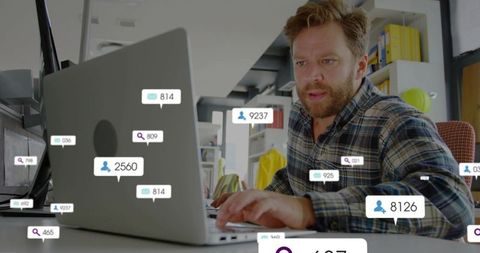 Bearded man typing on laptop with social media analytics overlays and notification badges