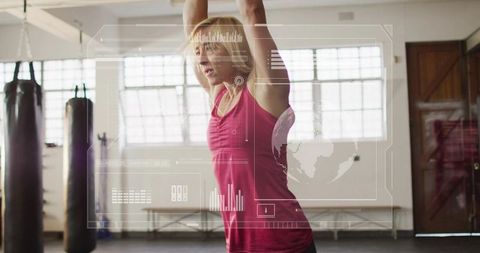 Woman training with hud overlay in boxing studio raising arms overhead, fitness focus