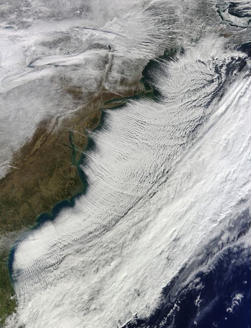 This captivating image from the Terra satellite's MODIS instrument showcases cloud streets forming over the Atlantic Ocean on January 7, 2014, due to a significant cold snap across much of the United States. The cold air flowing over the warmer ocean created long, parallel bands of cumulus clouds, forming an intriguing meteorological phenomenon. This image is ideal for use in scientific presentations, educational materials, meteorology research, and climate studies to illustrate atmospheric science concepts and the effects of temperature inversions.