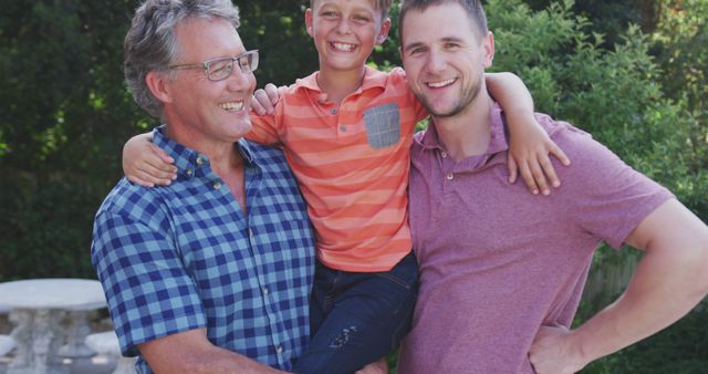 This image shows a happy multigenerational family with a grandfather, father, and son smiling together outdoors on a sunny day. Ideal for publications and websites focused on family life, generational bonds, happiness, and parenting. Perfect for marketing materials that emphasize togetherness, family values, and the joy of spending time with loved ones.