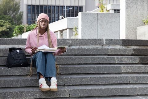 African American Student Studying on Urban Campus Steps Wearing Pink Hoodie and Beanie