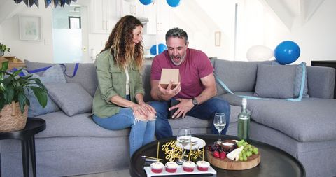 Couple celebrating birthday with gift and cake at home