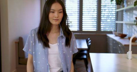 Elegant asian woman in contemporary kitchen with natural lighting