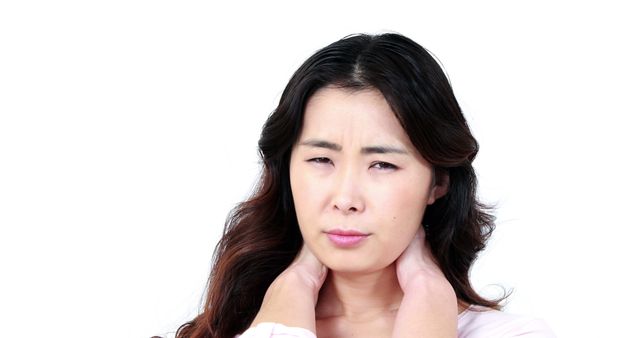 An Asian woman appears to be in discomfort, experiencing a sore throat or neck pain, with copy space. Her expression conveys concern or discomfort, which suggests she may be feeling unwell.