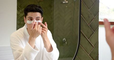 man applying under eye patches in modern bathroom for skincare routine - Download Free Stock Images Pikwizard.com