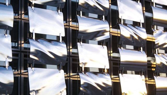 Curved chrome facade panels reflecting sky on modern architectural grid