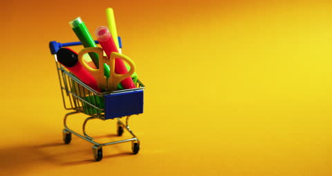 Miniature Shopping Cart with Colorful School Supplies on Yellow