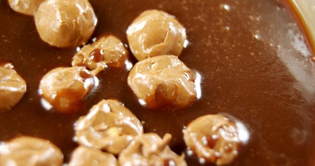 Close-up view of a creamy peanut butter cup filling with whole peanuts embedded, showcasing the texture and glossy surface. This delicious detail highlights the indulgent combination of smooth chocolate and crunchy nuts in a popular confectionery treat.