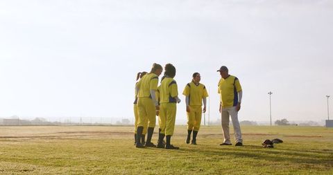 Diverse softball team listening to coach during game strategy