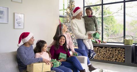 Multigenerational diverse family sharing Christmas gifts in cozy modern living room