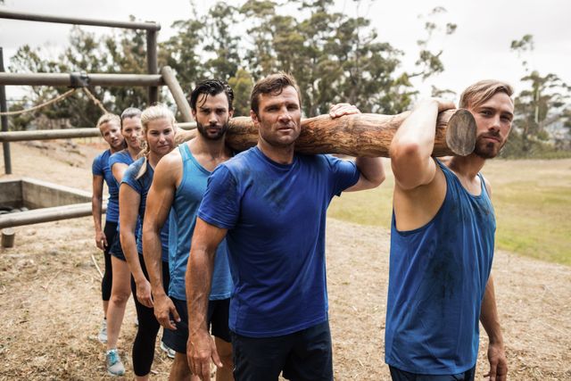 Fit people carrying a heavy wooden log during boot camp training