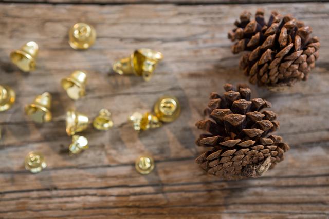 Christmas bells and pine cones on wooden plank creating a rustic holiday decoration. Ideal for use in holiday greeting cards, festive blog posts, or seasonal marketing materials.