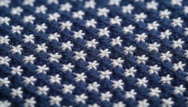 Macro navy blue needlework with white star stitches creating repeating textured pattern