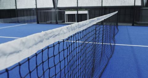 Focused tennis net on blue court surface with bench