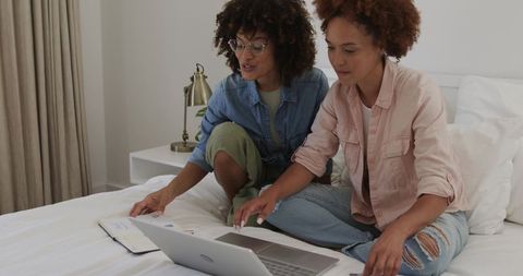 African American Women Collaborating on Laptop in Cozy Bedroom Workspace