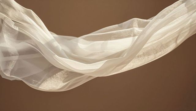 Floating sheer fabric creating soft layered ribbons and warm highlighted textures