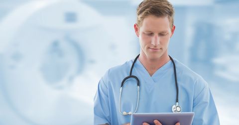 Male Doctor in Scrubs Using Digital Tablet in Hospital Setting