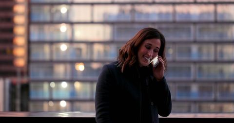 Caucasian businesswoman on balcony talking on phone during evening