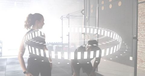 Backlit fitness partners resting after workout in gym with digital circular rings overlay