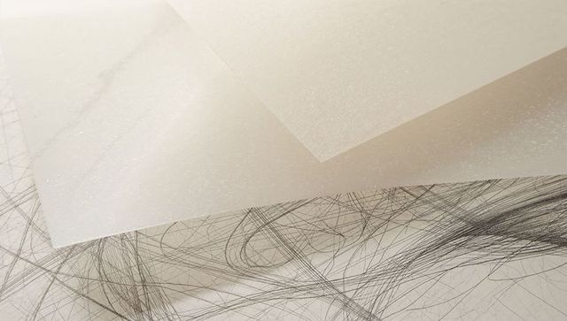 Translucent tracing paper layers with graphite scribbles and textured vellum overlap