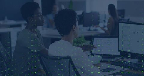 Two Women Collaborating on Data Analytics at Open-Plan Office with Binary Code Overlay